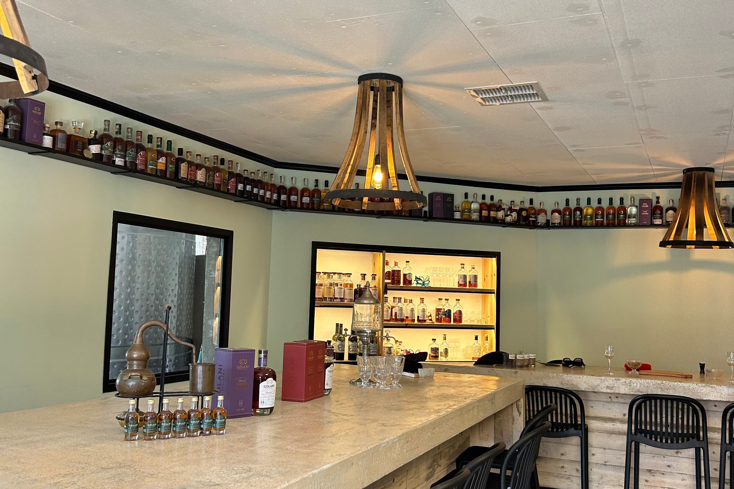 Bar area with a long counter, stools, and shelves stocked with bottles.